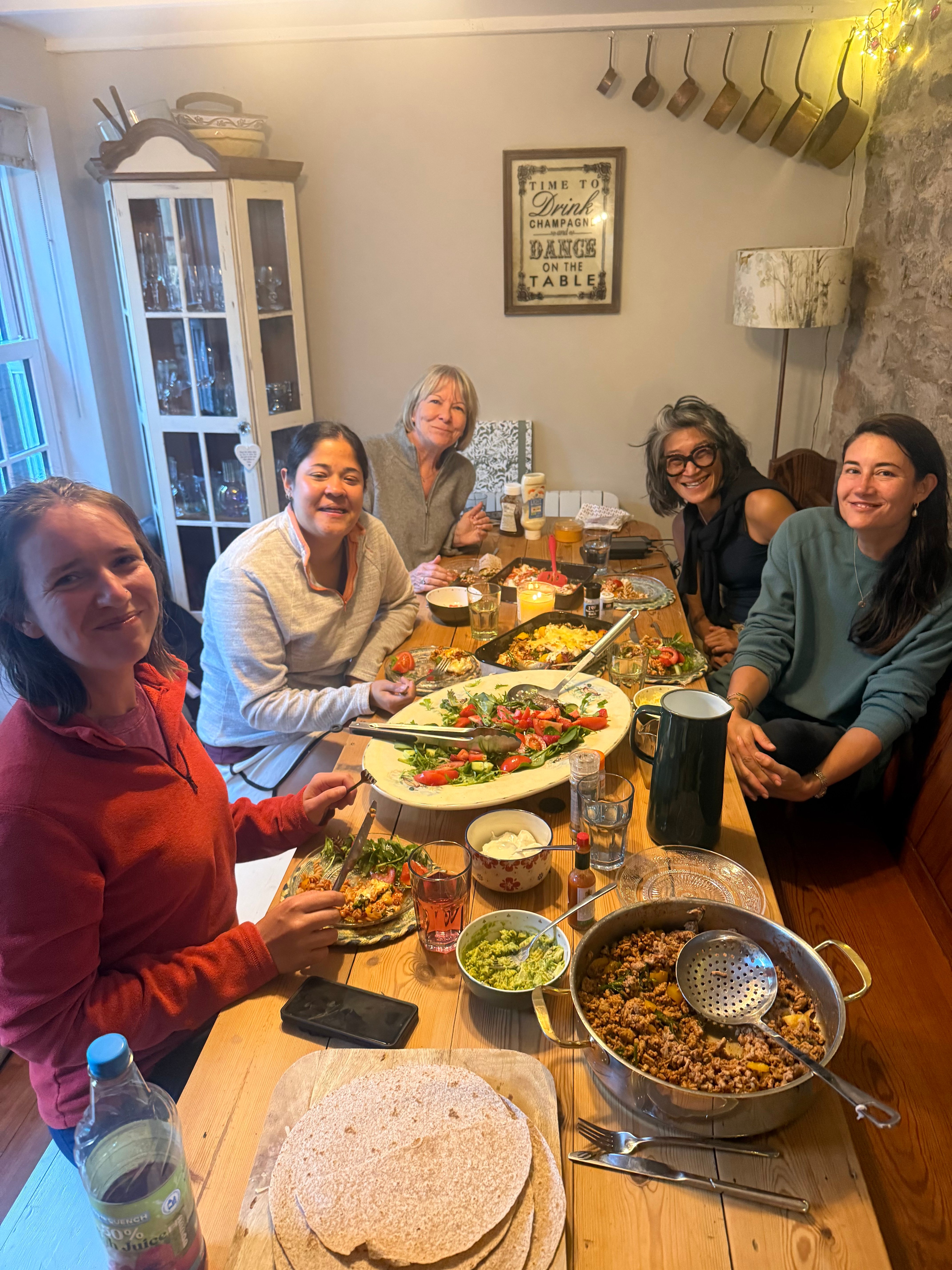 Women gathered around a long wooden table for a candlelit communal dinner