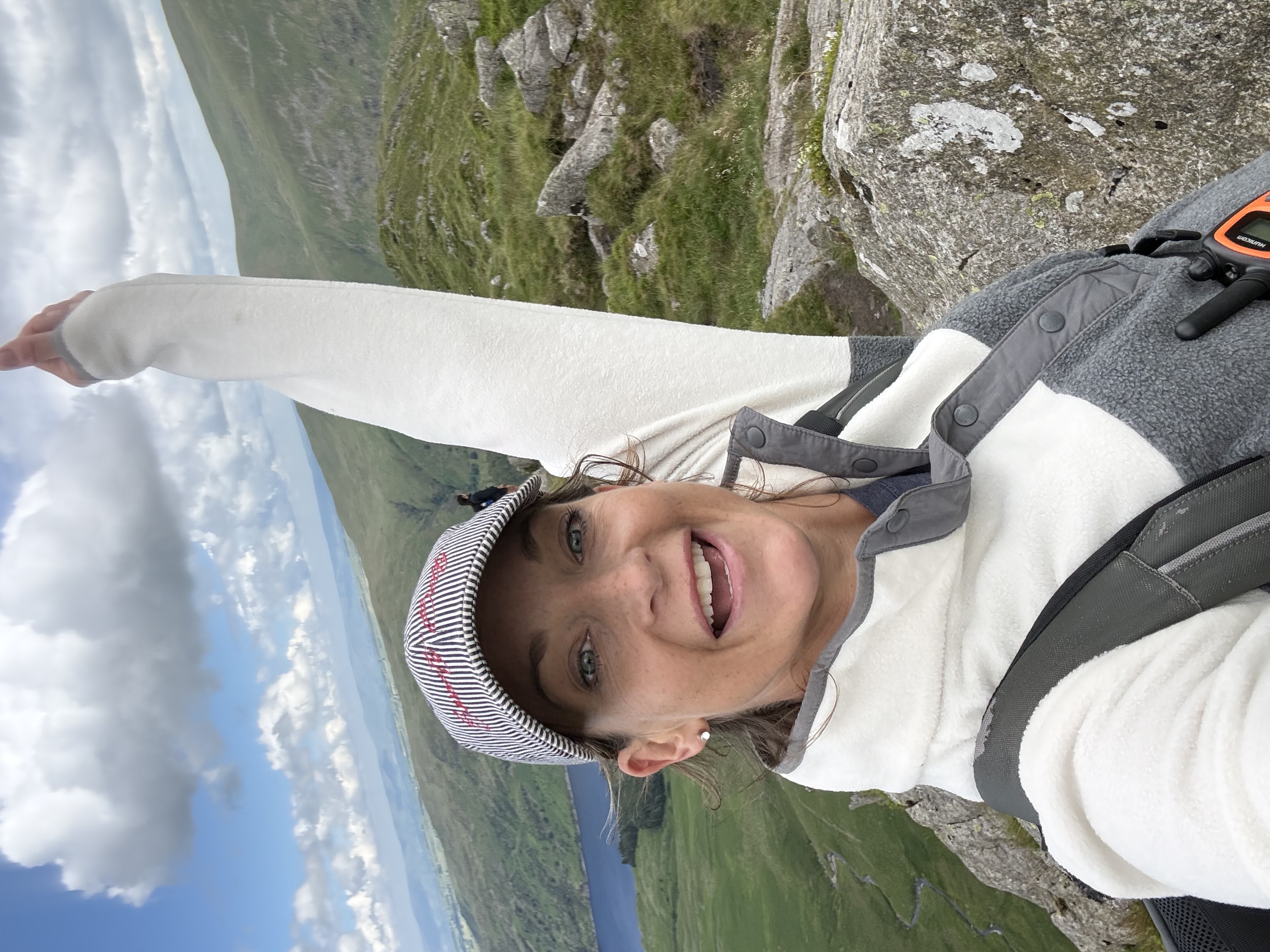 Joyful summit selfie with an arm raised in celebration, the lake far below